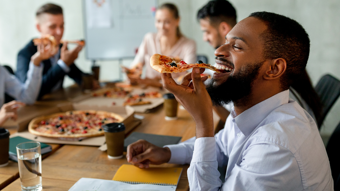 Menschen sitzen an einem Tisch zusammen und essen Pizza
