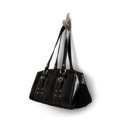 À un crochet en métal Command™ "classique" de 3M Deutschland GmbH est suspendu un sac à main en cuir noir avec des poignées doubles et des boucles décoratives. Le sac a des coutures blanches et une surface légèrement brillante.