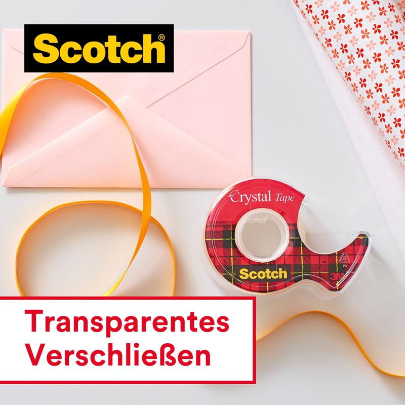 Eine Packung Scotch® Crystal Klebeband (19mm x 25m + 5m GRATIS) auf Handabroller von 3M Deutschland GmbH, ein pinker Umschlag, gelbes Band und Geschenkpapier liegen auf weißem Hintergrund. Im Bild: "Transparentes Verschließen.