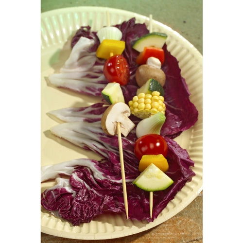 Deux brochettes de légumes sur PAPSTAR 250 brochettes, bambou « pure » (PAPSTAR GmbH), remplies de champignons, tomates, maïs, courgettes, oignons et poivrons, reposent sur de grandes feuilles de radicchio sur une assiette en carton.