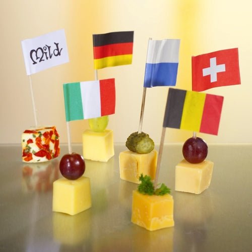 Fünf Käsewürfel, jeder mit einer einzigartigen Garnitur und einer anderen Flagge, sind auf einem hochwertigen und robusten PAPSTAR 100 Deko-Picker der PAPSTAR GmbH auf einer reflektierenden Oberfläche arrangiert – ideal für stilvolle Präsentationen bei jedem internationalen Event.