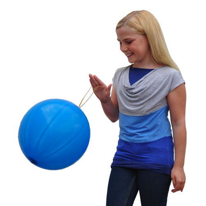 Une fille souriante aux longs cheveux blonds et à la chemise bleu-gris joue avec un grand ballon de punch PAPSTAR (Ø 40 cm, couleurs assorties, pack de 3) de la société PAPSTAR GmbH sur un fond blanc.