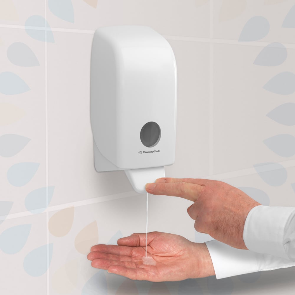 Une personne appuie sur un distributeur transparent de désinfectant pour les mains Kleenex® Extra Gel de Kimberly-Clark GmbH, monté sur un mur carrelé, et distribue le gel désinfectant pour les mains à partir d'une cassette de 1 litre sur sa paume ouverte.