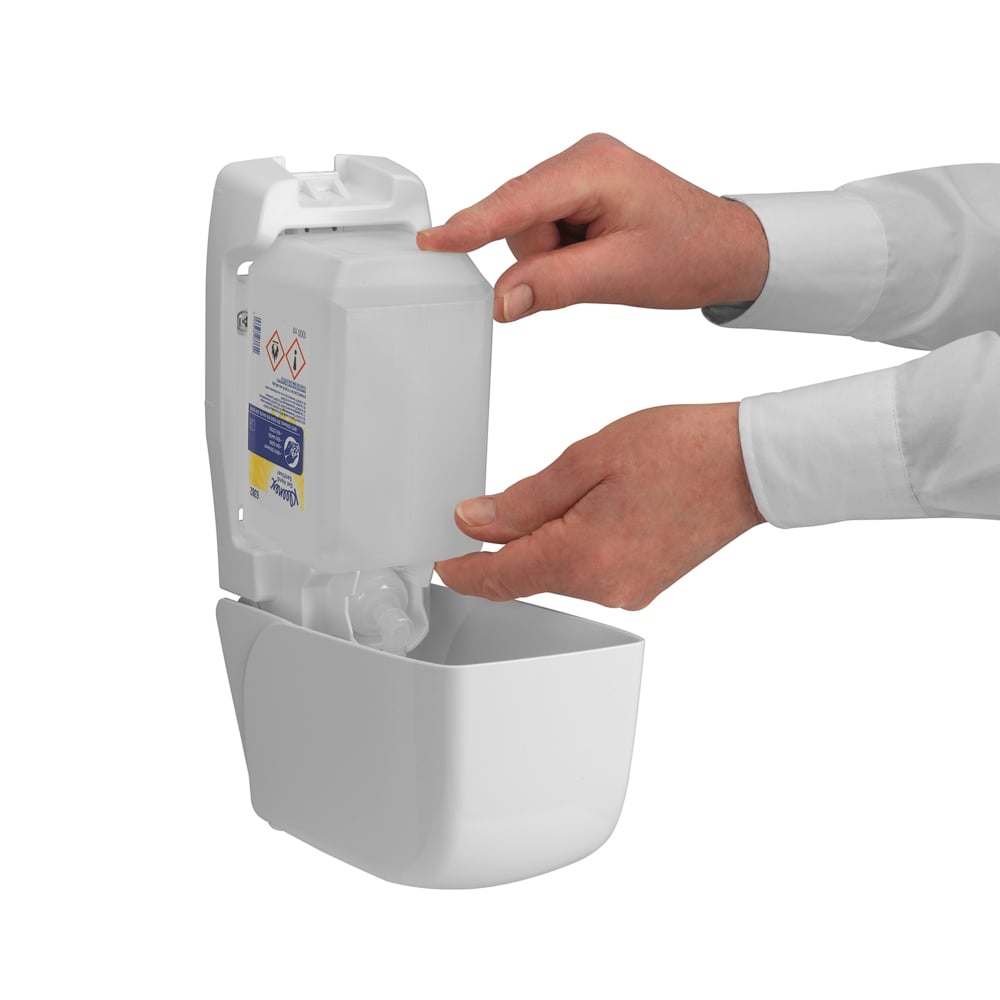 Une personne remplit un distributeur mural de désinfectant pour les mains Kleenex® Extra Gel de Kimberly-Clark GmbH en insérant une nouvelle cassette transparente de 1 litre avec ses deux mains ; seuls ses mains et avant-bras sont visibles à travers la face avant ouverte.