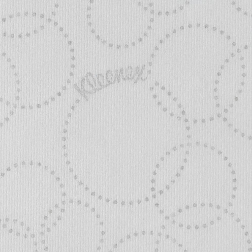 Die Nahaufnahme eines weißen Kleenex® Ultra™ Handtücher MultiFold Papiertuchs der Kimberly-Clark GmbH zeigt ein hellgraues, gepunktetes, kreisförmiges Muster, ein dezentes "Kleenex"-Branding zwischen den Punkten und eine leicht gerippte Textur.