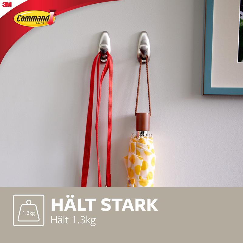 Deux crochets en métal Command™ "classique" de 3M Deutschland GmbH sont montés sur un mur blanc et tiennent une laisse rouge et un parapluie à motifs jaunes. Le texte indique : "TIENS FORT Supporte 1,3 kg" et montre le logo Command.