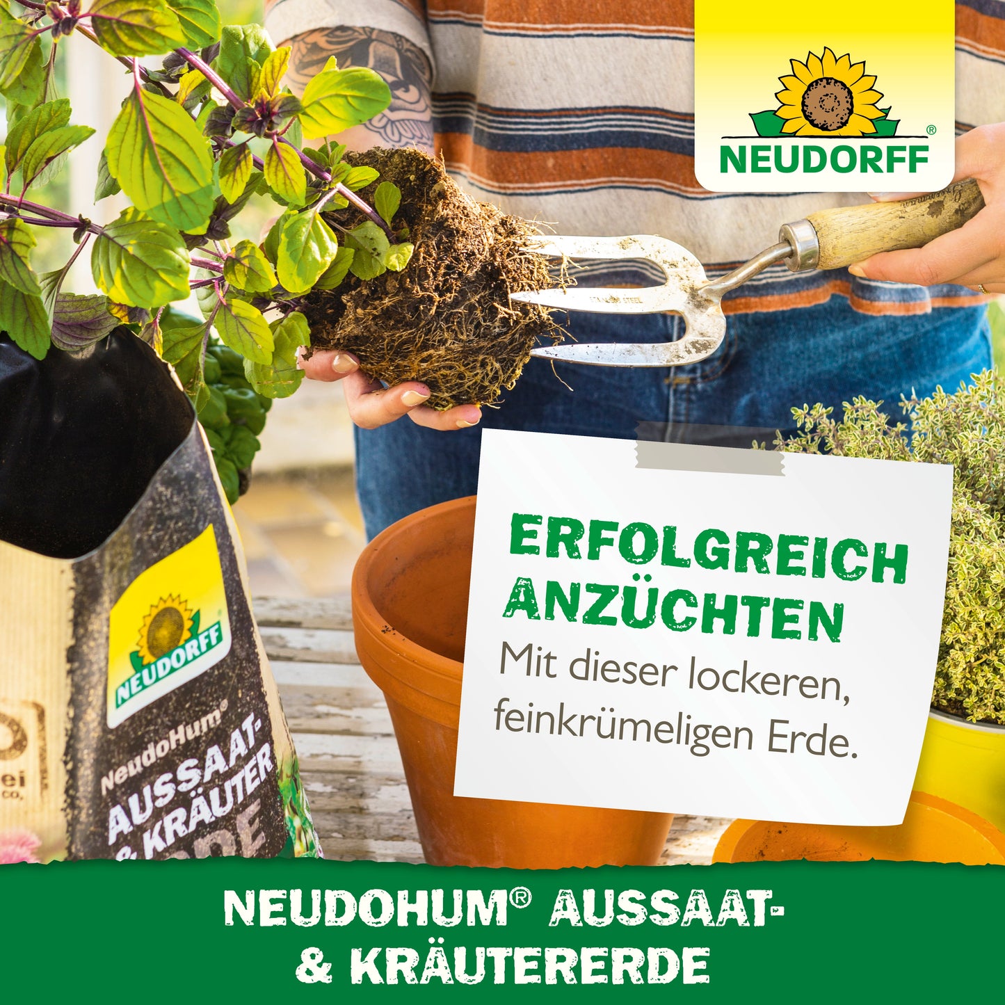 Eine Person benutzt eine Gartengabel, um die Erde in einem rechteckigen Pflanzgefäß vorzubereiten. Daneben steht eine Tüte mit NeudoHum Aussaat- & KräuterErde aus dem Neudorff Shop mit mediterranen Kräutern, Kräuterpflanzen, Branding und deutschem Werbetext.