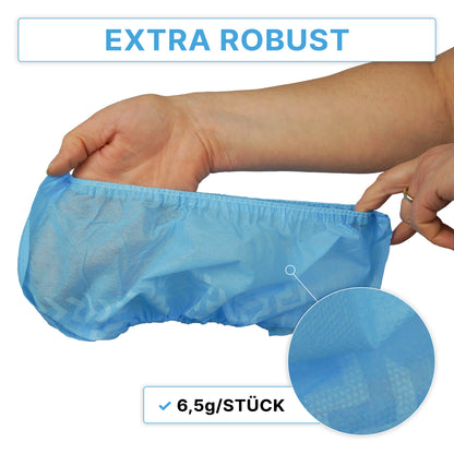 Une main tient une surchaussure bleue ARNOMED ABS, antidérapante, jetable de ARNOWA GmbH avec un motif structuré. En haut, le texte "EXTRA ROBUSTE" et en dessous "6,5g/PIÈCE", avec un gros plan du matériau de la surchaussure. Le sachet contient 100 pièces.