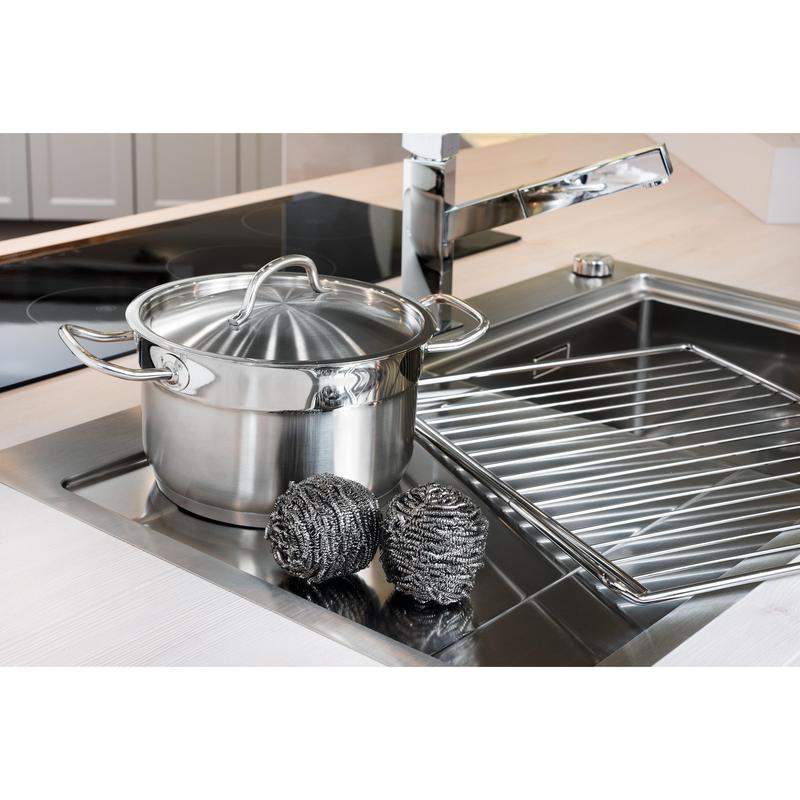 Une casserole en acier inoxydable avec couvercle est placée dans l'évier à côté de deux spirales en acier inoxydable Scotch-Brite® (3M Deutschland GmbH, 3 pièces par paquet) et d'un égouttoir - pour un nettoyage facile de la cuisine même en cas de salissures tenaces.