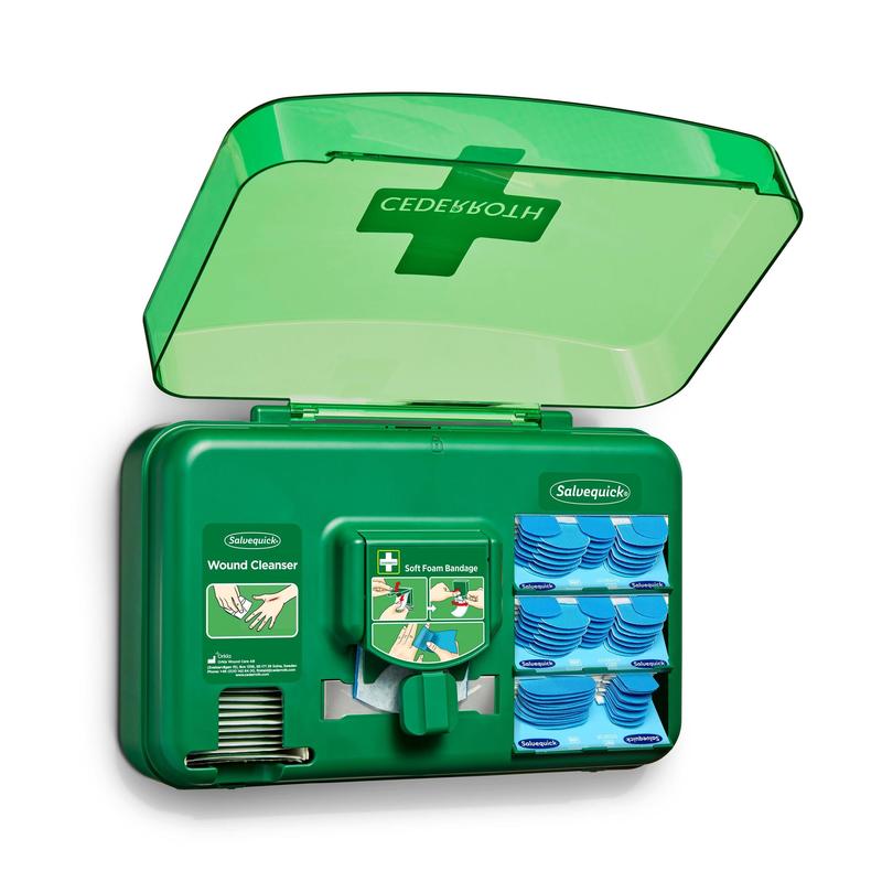 Un distributeur de soins des plaies bleu d'Orkla Wound Care AB est ouvert et dévoile des paquets de nettoyage des plaies, des pansements et un rouleau de bandes en mousse douce, disposés dans des compartiments individuels.