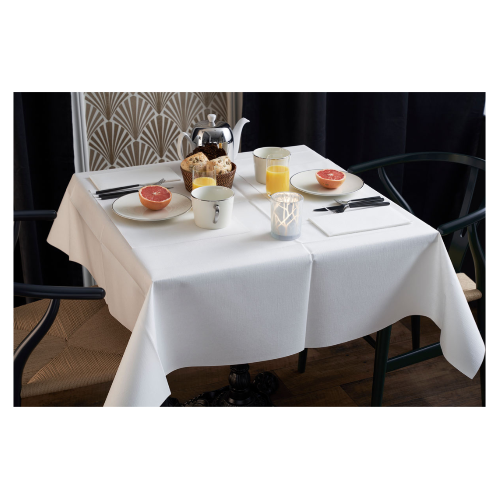 Der Frühstückstisch ist elegant gedeckt mit einer weißen Tischdecke, zwei Stühlen und einer Vase mit geometrischem Muster. Auf dem Tisch stehen Grapefruithälften, Gebäck, Tee und Orangensaft. Eine Duni Dunilin®-Serviette (48x48 cm) von Duni GmbH verleiht dem stimmungsvollen Morgengedeck Charme und Funktionalität.