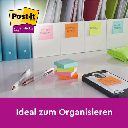 Ein Schreibtisch mit Ordnern, beschriftet mit bunten Post-it® Super Sticky Notes Würfeln in Gelb (76 x 76 mm) von 3M Deutschland GmbH, Stifte, Textmarker und Smartphone auf einem Notizblock. Text: "Ideal zum Organisieren.