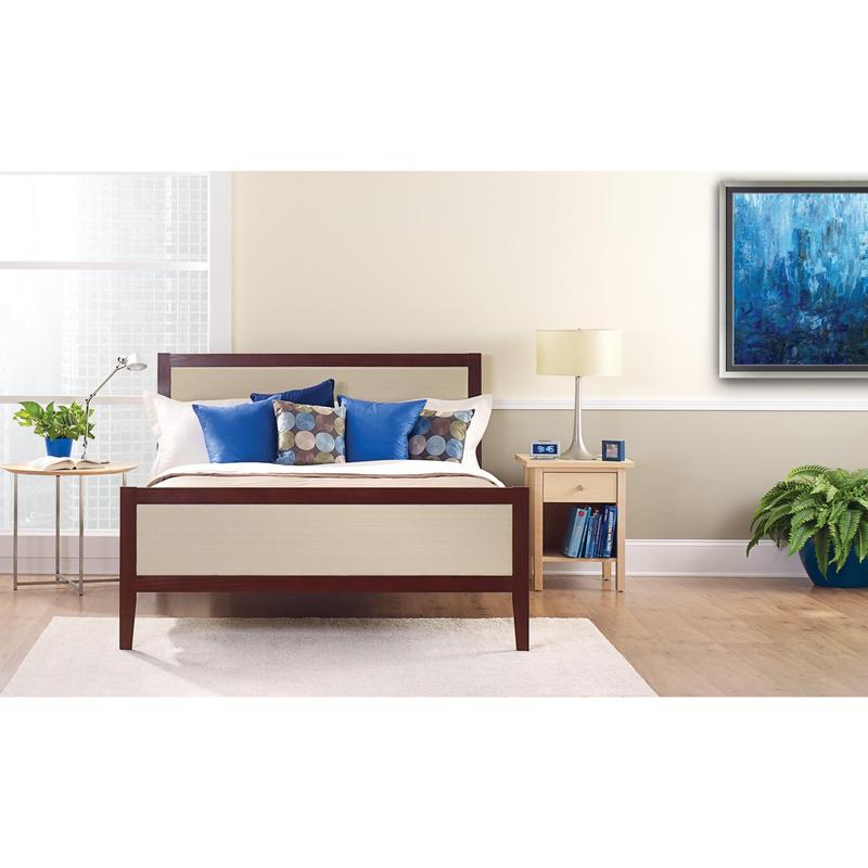 Un lit bien fait avec des oreillers blancs et bleus se trouve devant un mur clair, recouvert de ruban de masquage ScotchBlue™ "Multi-Surface" de 3M Deutschland GmbH. Sur une table de chevet, il y a une lampe, une horloge, des livres et une plante en pot à côté de la fenêtre lumineuse.