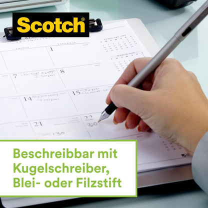 Eine Hand schreibt auf einen Kalender, während der 3M Scotch™ Edelstahl-Klebebandabroller, Silber und Scotch® Magic™ Klebeband (66% pflanzenbasierter Klebstoff) danebenliegt. Unten steht: "Beschreibbar mit Kugelschreiber, Blei- oder Filzstift.