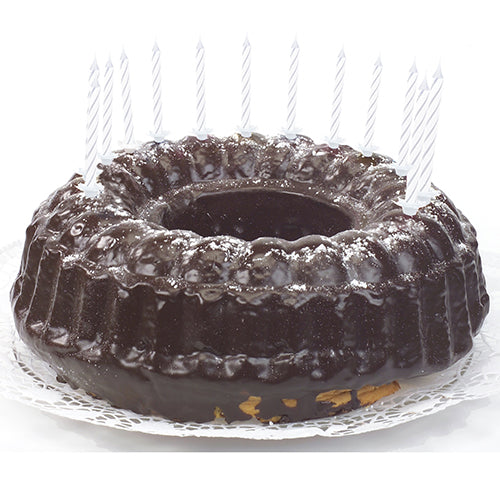Un gâteau au chocolat avec un glaçage brillant, décoré avec des bougies d'anniversaire PAPSTAR GmbH de 6 cm, blanches avec support (24 pièces), réparties uniformément sur le bord et reposant sur un napperon en dentelle blanche.