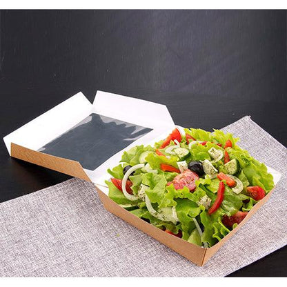 Les PAPSTAR 25 boîtes de produits fins en carton avec fenêtre en PLA de PAPSTAR GmbH présentent une salade fraîche avec tomates, oignons, olives et herbes présentée avec style sur un tissu gris sur fond sombre.