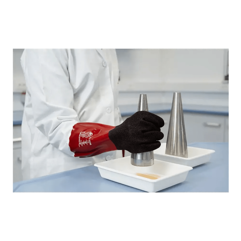Eine Person im Laborkittel und roten AMPri SolidSafety Chem MaxGrip Chemikalienschutzhandschuhen M - L hält vorsichtig einen Metallkegel über eine weiße Schale. Eine identische Schale mit einem eigenen Metallkegel steht daneben auf der blauen Labortischplatte und gewährleistet den Schutz vor Säuren während des gesamten Experiments.