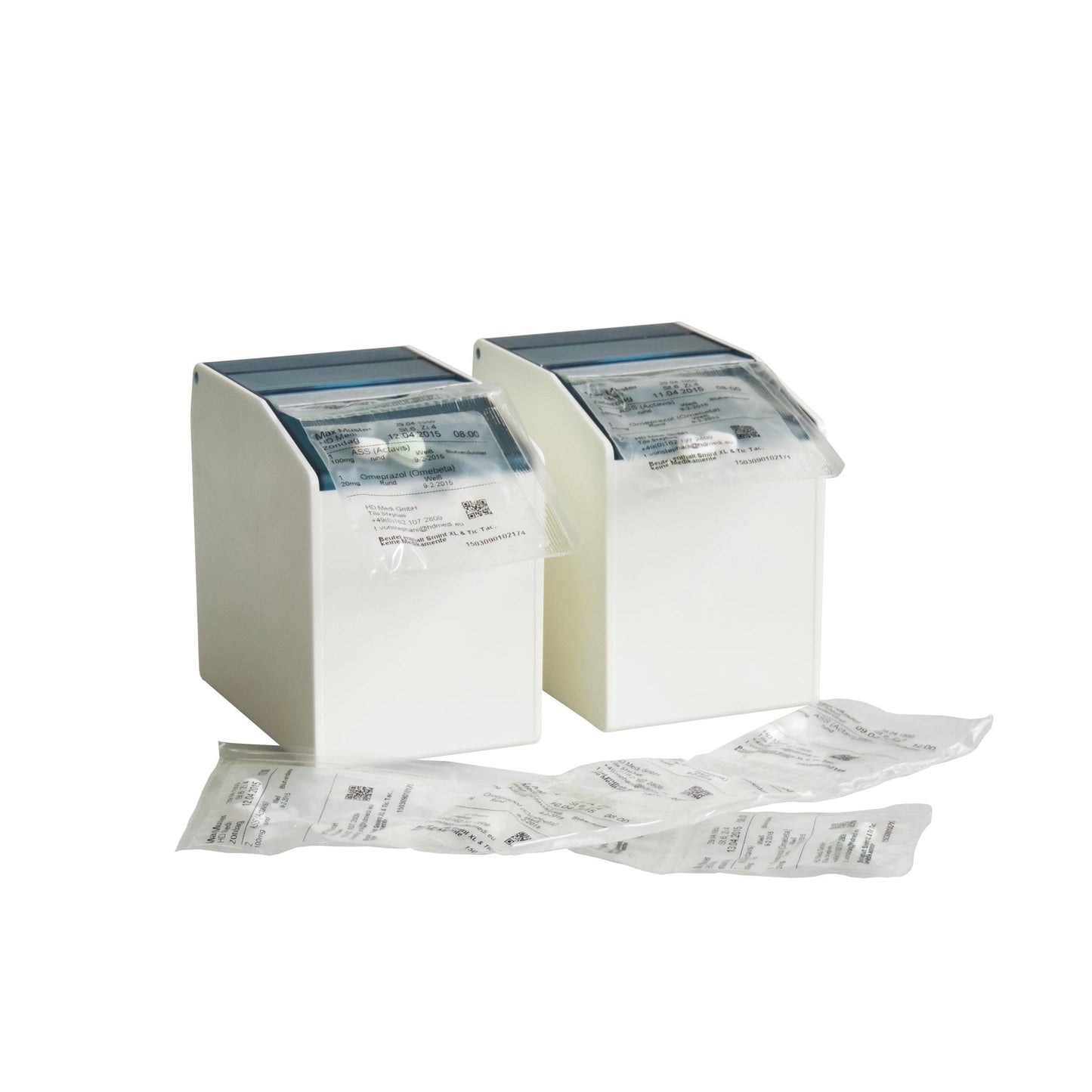 Deux distributeurs de boîtes à blister Novocal blancs (1 rabat avant flexible, 2 bandes magnétiques à l'arrière, 80 mm, 1 paquet) accueillent des emballages de médicaments scellés, avec des paquets supplémentaires de petits produits sur une surface blanche devant un fond uni.