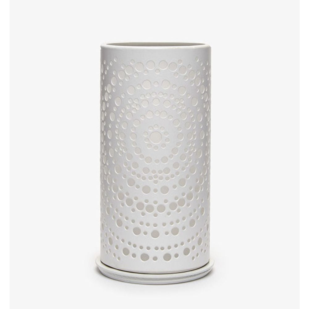 Un vase cylindrique blanc avec un motif de points concentriques perforés moderne, rappelant le photophore Billy en métal de Duni GmbH, se trouve devant un fond blanc simple.
