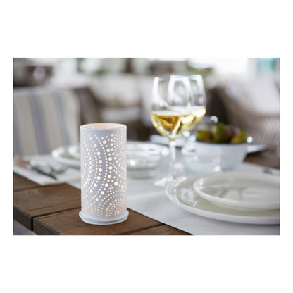 Sur une table à manger se trouvent des assiettes blanches, des couverts et des verres à vin avec du vin blanc. Au premier plan, le photophore Billy en métal 140 x 75 mm avec un motif de points de Duni GmbH est bien en évidence, et à l'arrière-plan, un bol avec des raisins.