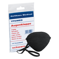 L'objet exposé est un cache-œil Holthaus Ypsimed, muni d'un élastique, en tissu noir. À côté se trouve un emballage en plastique portant les inscriptions « Holthaus Medical GmbH & Co. KG », « YPSIMED » et « cache-œil » en plusieurs langues, ce qui indique qu'il s'agit d'un dispositif médical destiné à la protection des yeux.
