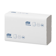 Une pile de serviettes multifold Tork Xpress® 471093 Universal H2 est visible sur un fond blanc simple. L'emballage, qui porte le logo bleu TORK de Essity Professional Hygiene Germany GmbH, montre des symboles indiquant l'utilisation des serviettes multifold. La pile rectangulaire présente un bord ouvert visible, soulignant son design pratique.