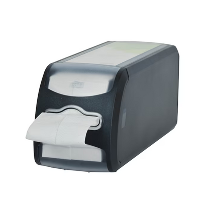 Un distributeur de comptoir en plastique noir pour serviettes Tork Xpressnap Fit® 272901 de TORK - Essity Professional Hygiene Germany GmbH dispose d'une partie avant transparente sur laquelle est visible une pile de serviettes blanches, dont une dépasse par l'ouverture. Son design permet la distribution de feuilles individuelles et est monté sur un fond blanc.