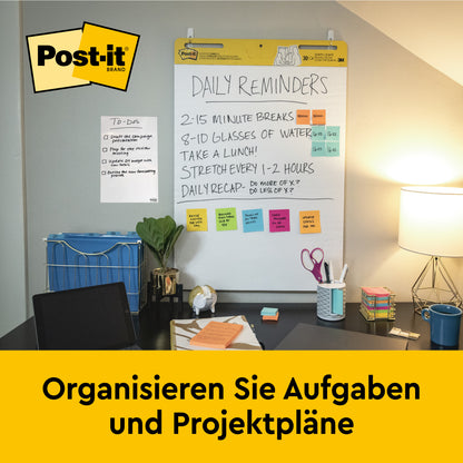 Ein aufgeräumtes Büro mit einem 3M Post-it® Super Sticky selbsthaftendes Meeting Chart 559P (63,5x76,2 cm, weiß) mit neonfarbenen Meeting Notes, Schreibwaren, Lampe und Stuhl. Auf einem gelben Banner steht: "Organisieren Sie Aufgaben und Projektpläne.