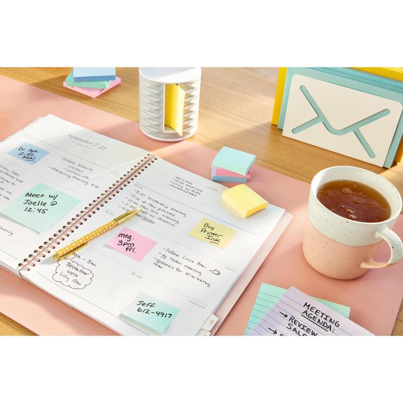 Un planificateur ouvert avec des notes manuscrites, un stylo, des notes de recyclage Post-it® 3M Deutschland GmbH (76 mm x 127 mm, 100% PEFC), une tasse de thé, une fiche avec l'inscription "AGENDA DE RÉUNION" et des accessoires de bureau sur un sous-main rose clair.