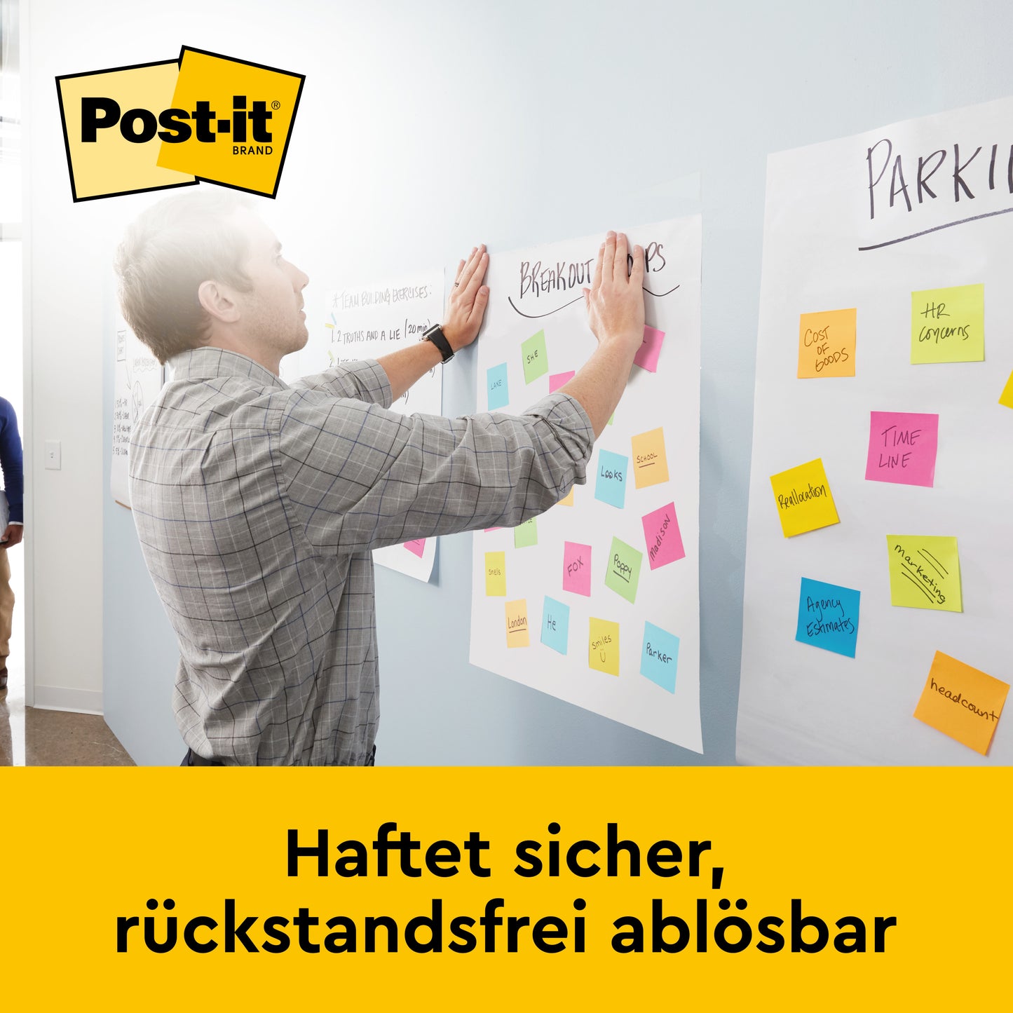 Ein Mann klebt bunte Zettel an eine Wand neben einem Post-it® Super Sticky selbsthaftendes Meeting Chart/Flipchart mit Aufsteller (58,4x50,8 cm, 20 Blatt, 6 Blöcke), von 3M Deutschland GmbH. Oben das Post-it Logo, unten: "Haftet sicher, rückstandsfrei ablösbar.