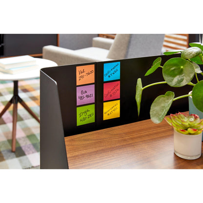 Sur un bureau en bois se trouvent cinq Post-it® Super Sticky Z-Notes colorés (76 x 76 mm, 90 feuilles/bloc) de 3M Deutschland GmbH. À côté d'eux se trouvent une plante en pot et une succulente. À l'arrière-plan : table, chaises, tapis à carreaux.