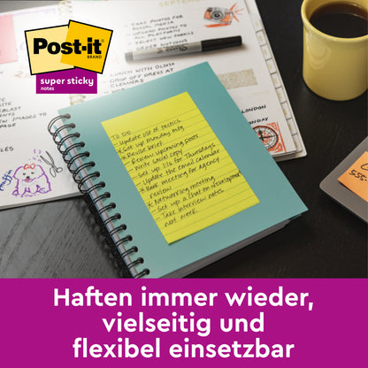 Ein Spiralnotizbuch mit Post-it® Super Sticky Notes der 3M Deutschland GmbH im Großformat, Grün, Liniert (101x101 mm, 70 Blatt), liegt auf einem Schreibtisch neben einem Kalender, Papieren, einer Kaffeetasse und Stiften. Text: "Haften immer wieder, vielseitig und flexibel einsetzbar.