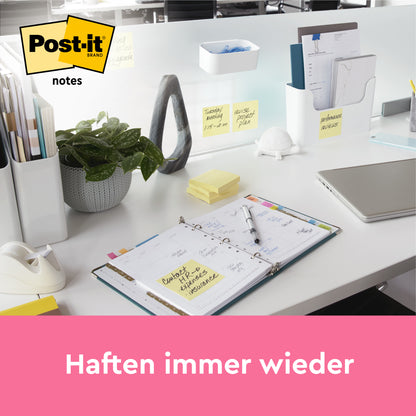 Un bureau bien rangé avec des fournitures de bureau de 3M Deutschland GmbH, une plante, un planificateur ouvert, des notes Post-it® jaunes (101 mm x 101 mm, 200 feuilles) sur une plaque mate et un ordinateur portable. En bas, il est écrit "Adhère à plusieurs reprises" sur un ruban rose.