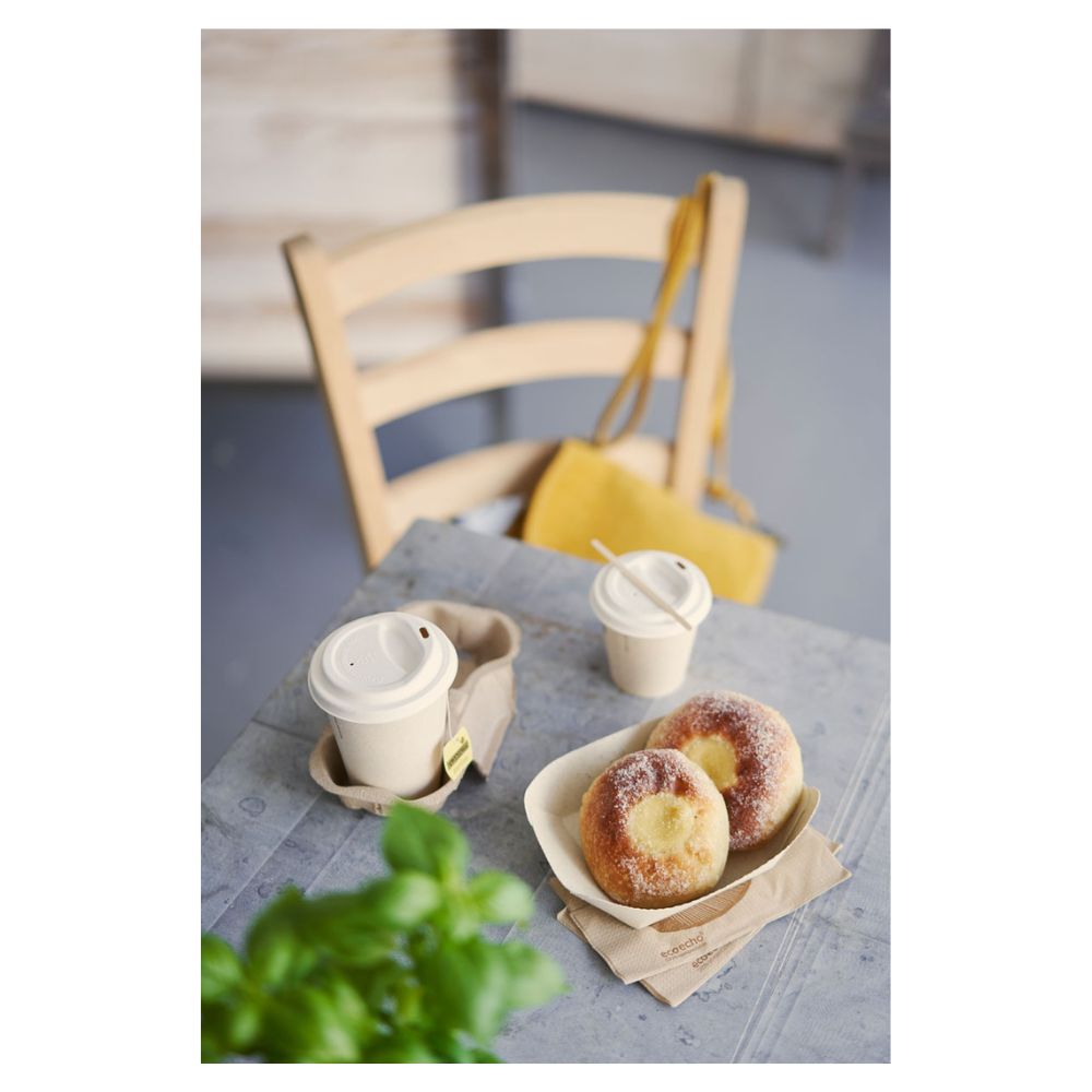 Sur une table se trouvent deux pâtisseries saupoudrées de sucre sur un plateau et deux gobelets à café Duni « Sweet imprimé en bagasse » avec couvercles de Duni GmbH. Un sac à main jaune est accroché à une chaise en bois, tandis qu'une plante verte partiellement visible au premier plan met en valeur le thème subtil de la durabilité.
